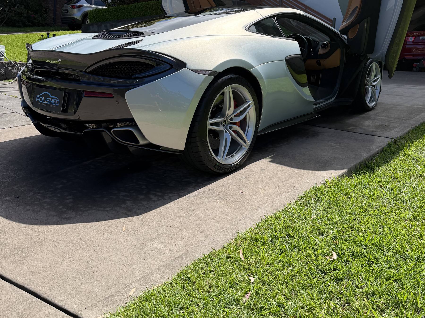 McLaren 570S rear three quarter view with the doors open after a detail